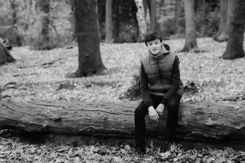 teenager sits on fallen tree in park during autumn. image used as an example of the megapixels needed for your camera