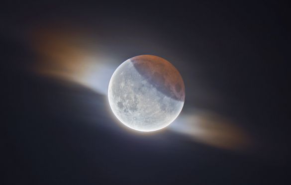 HDR Partial Lunar Eclipse with Clouds © Ethan Roberts (UK) - RUNNER-UP
During the 2019 partial lunar eclipse, the photographer managed to capture this fantastic image of the Moon while a small cloud passed in front of it. You can see the Earth's shadow on the top right and its striking orange colour caused by the Sun’s light passing through the atmosphere. This is a high dynamic range image, meaning both the darker, shadowed region is correctly exposed as well as the much brighter parts of the Moon. This processing technique also allows the clouds to be seen more clearly, giving the Moon a similar appearance to that of a solar corona.
Sky-Watcher Evostar 80ED telescope, Sky-Watcher EQ5 SynScan mount, Canon EOS 100D camera, 600 mm f/7 lens, ISO 800, composite of 5-second, 1-second, 1/10-second and 1/30-second exposures
